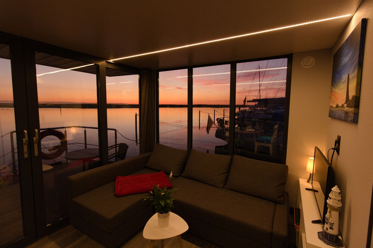 Wohnbereich in einem Hausboot. Im Hintergrund geht die Sonne unter.
